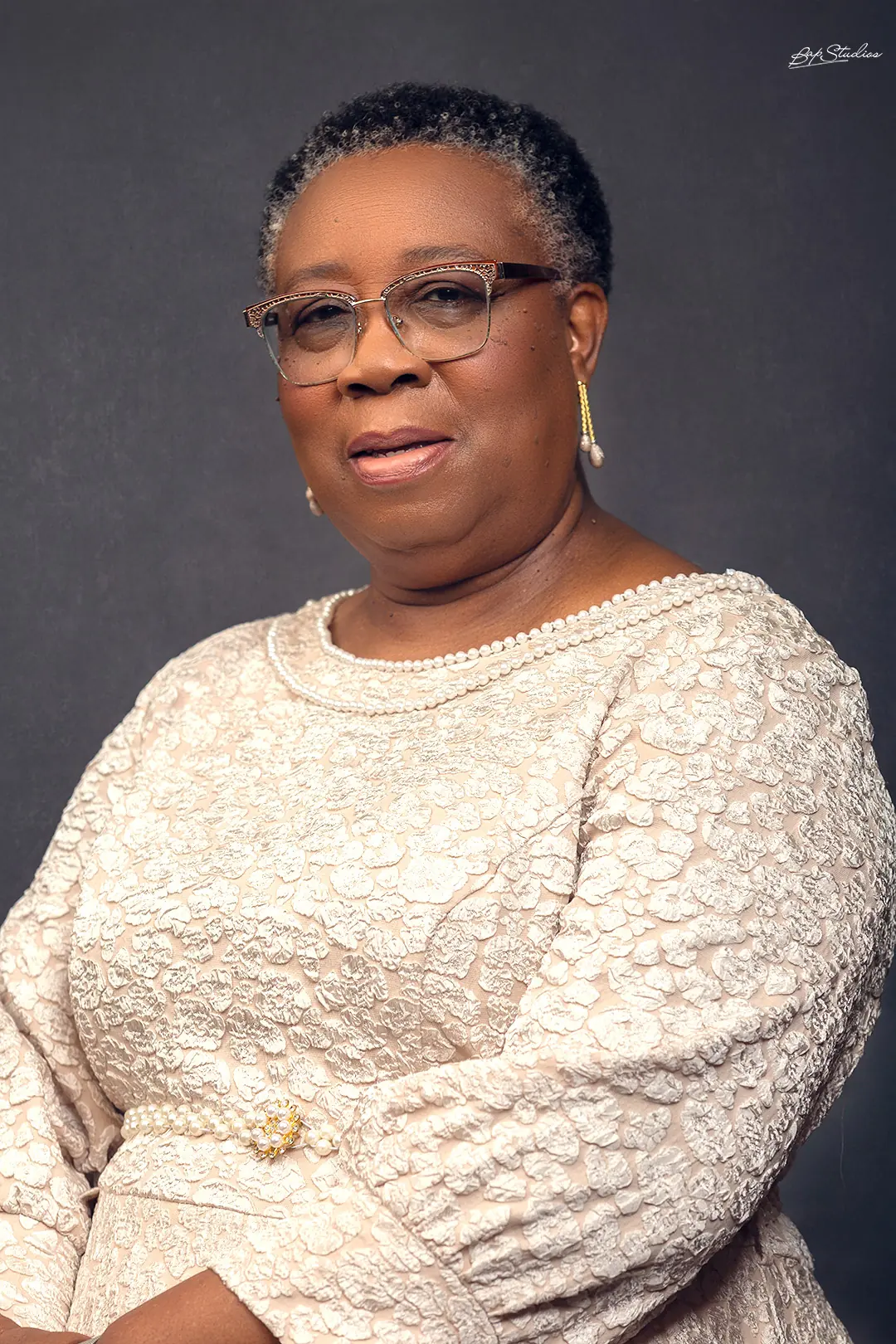 Folasade Adefisayo in a cream lace dress against a slate-blue backdrop.