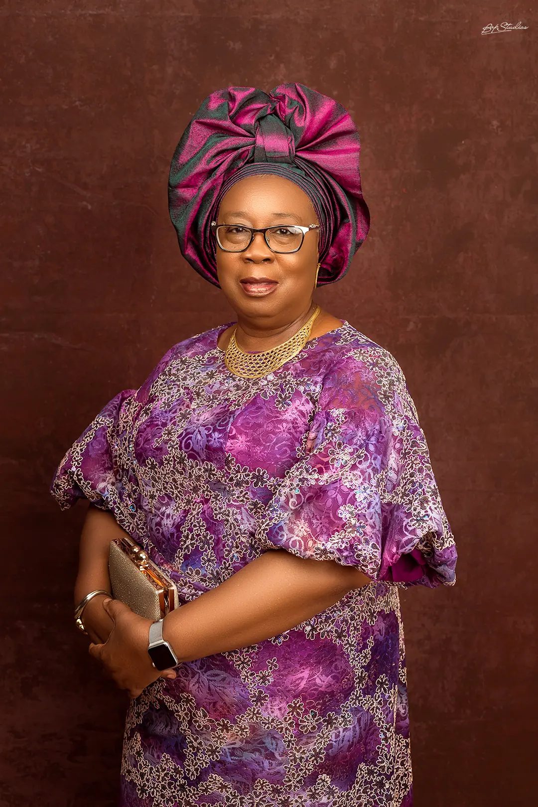 Folasade Adefisayo in a violet and gold patterned gown with a matching gele.