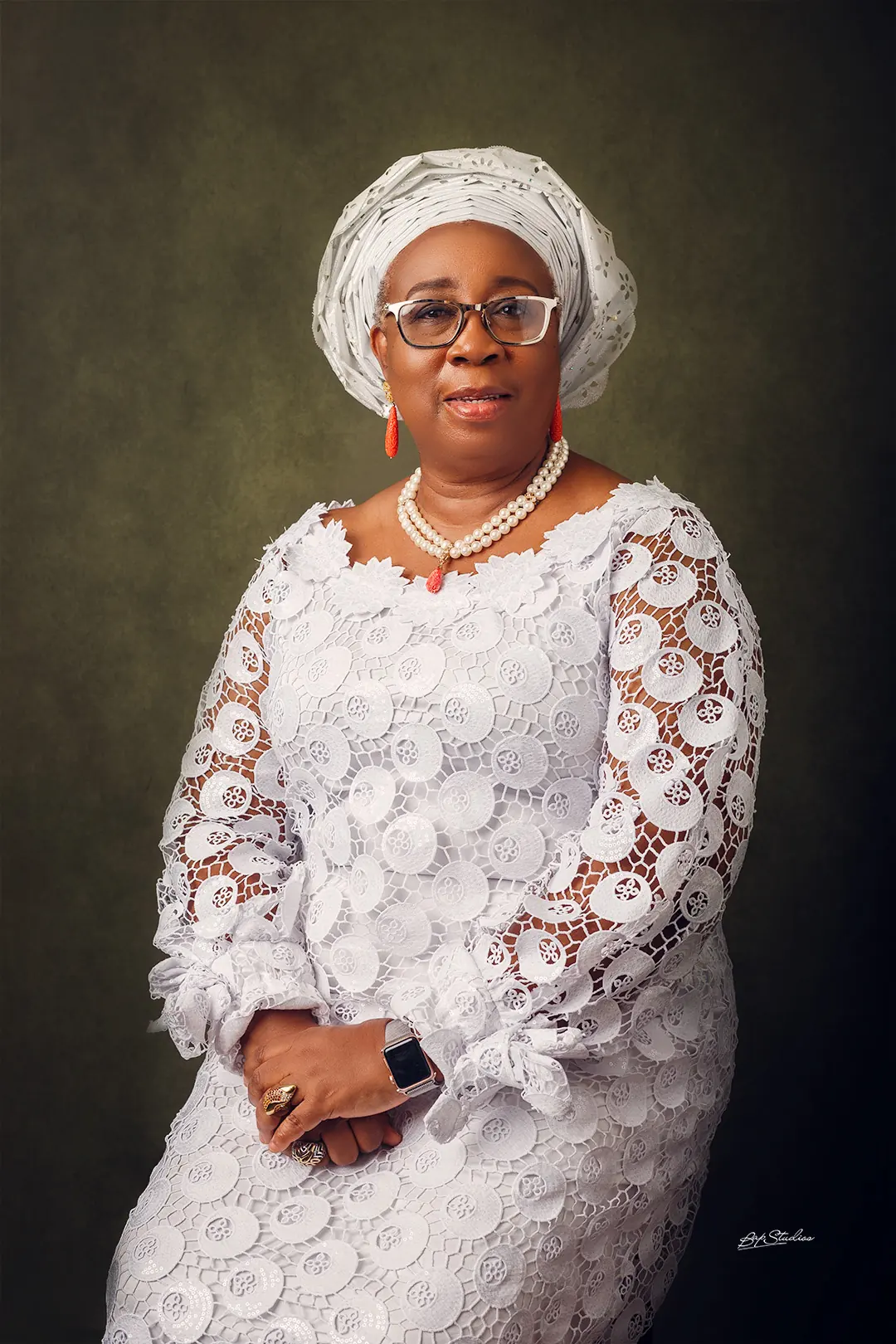 Folasade Adefisayo in an ivory lace buba and matching gele, seated against an olive backdrop.