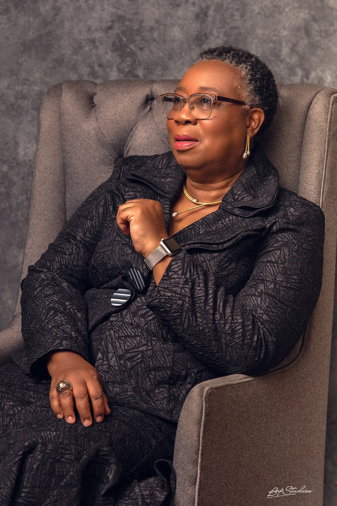 Folasade Adefisayo seated, looking away from the camera, in a dark jacket.